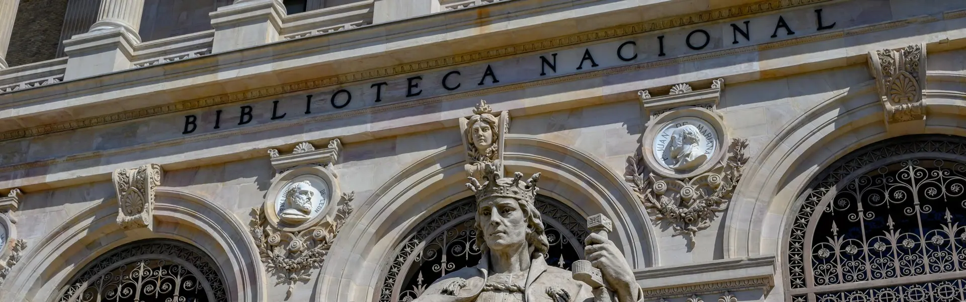 Fachada de la Biblioteca Nacional de Madrid con la estatua sedente de Alfonso el Sabio y, a los lados, las de Luis Vives y Lope de Vega