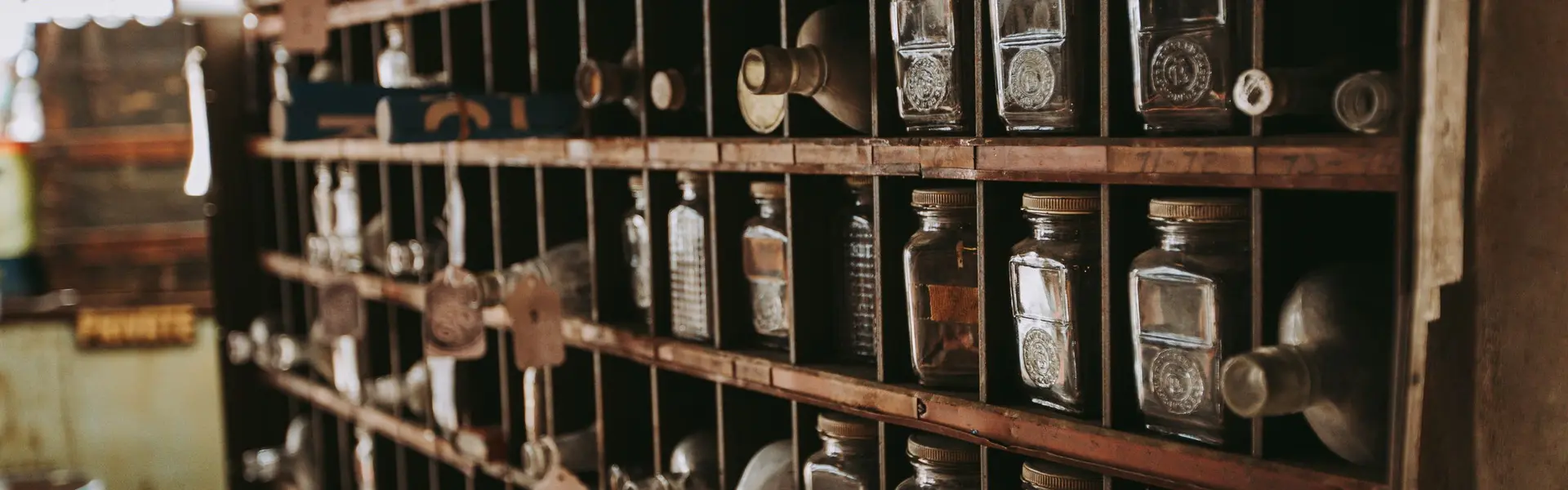 Estantería de madera con botellas y tarros de vidrio ordenados en sus casillas