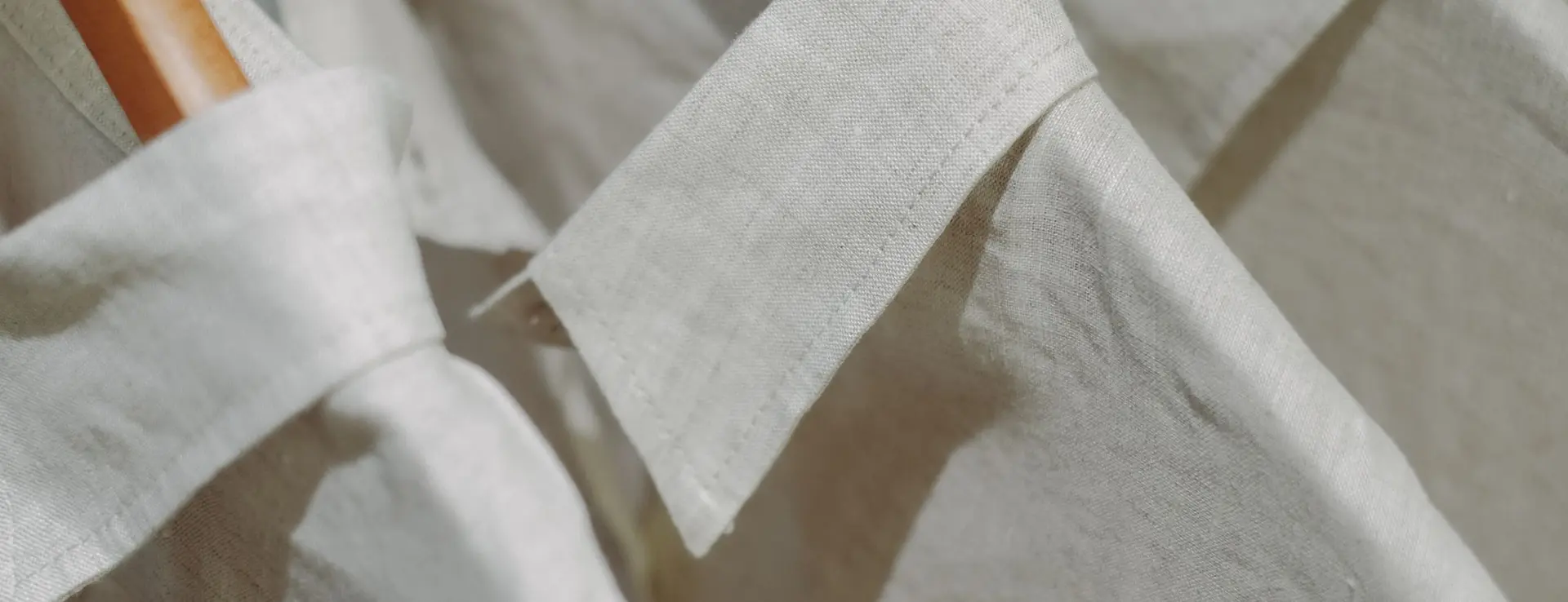 Camisas de lino crudo en perchas de madera, con los cuellos en primer plano