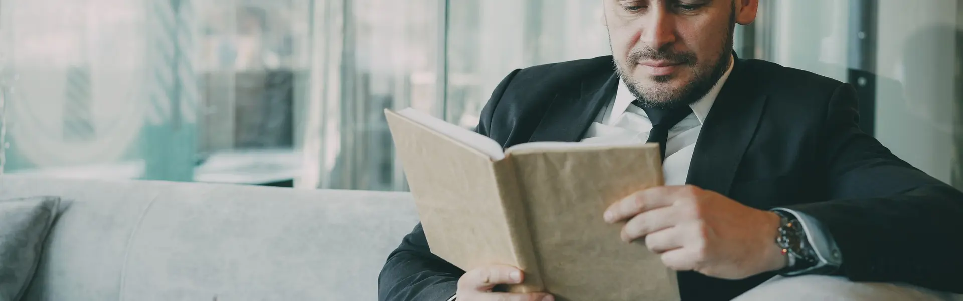 Empresario de traje leyendo un libro sentado en el salón de un café