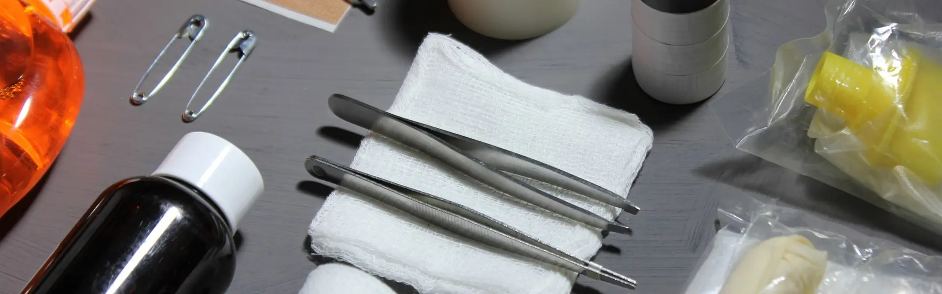 Material de curas ordenado sobre una mesa: tijeras, esparadrapo, gasas, pinzas, imperdibles, vendas y antisépticos