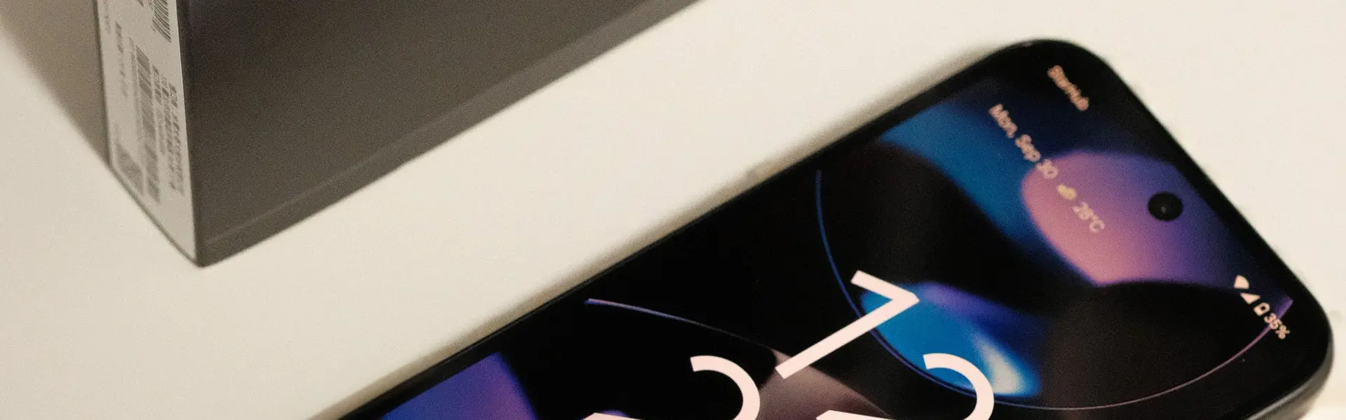 Google Pixel 9 con la pantalla de bloqueo encendida sobre una mesa blanca, junto a su caja