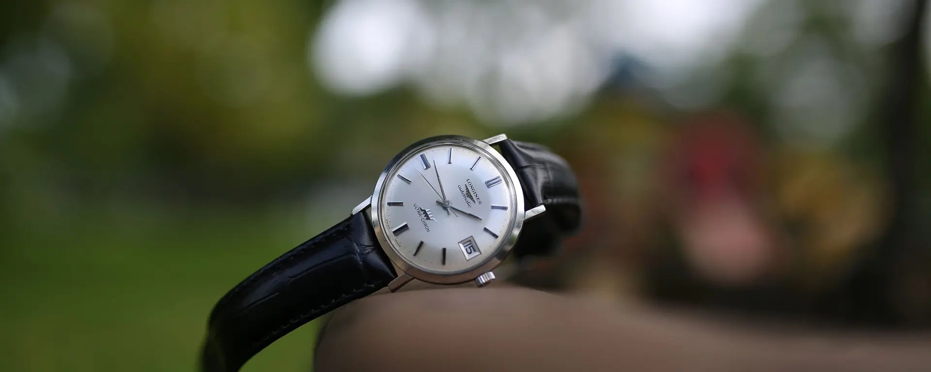 Reloj clásico con correa de cuero negro sobre fondo natural