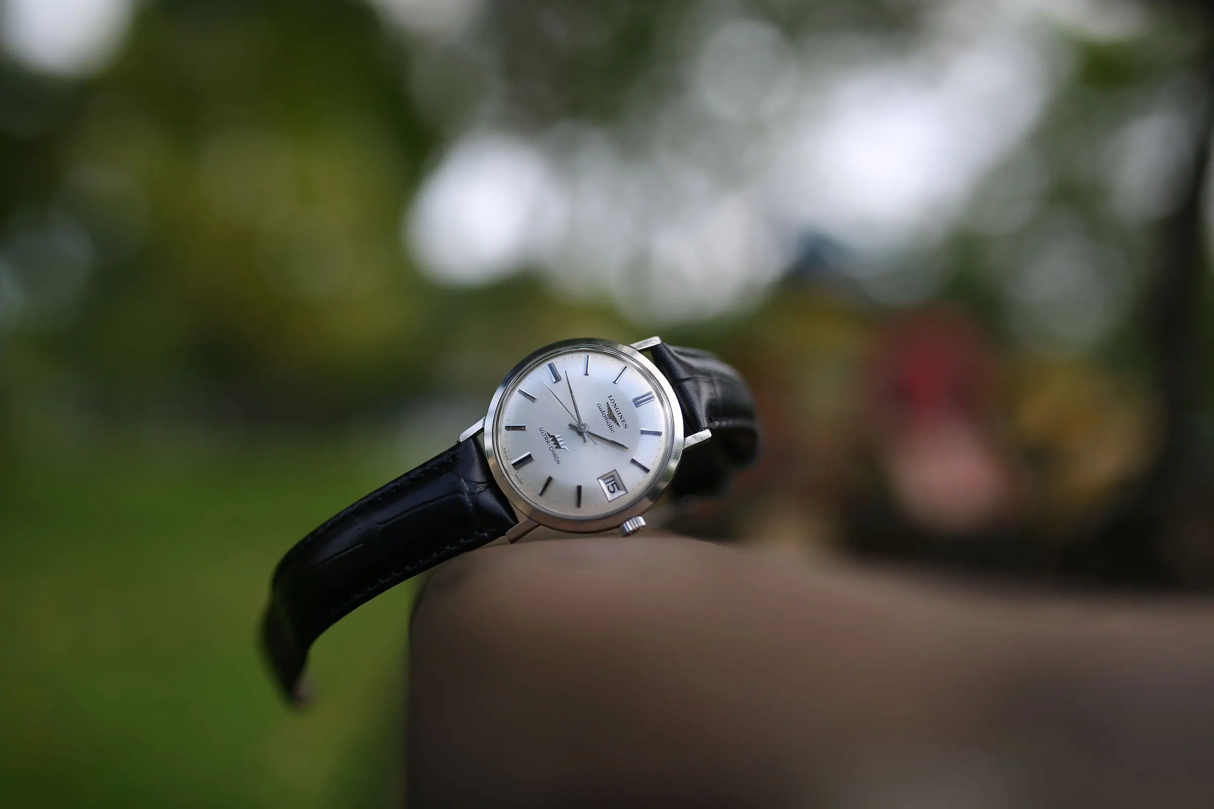 Reloj clásico con correa de cuero negro sobre fondo natural