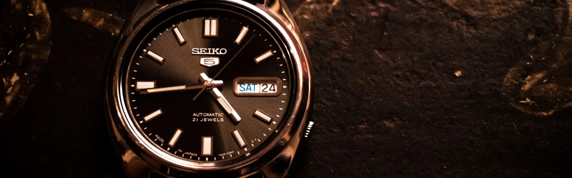 Seiko 5 automático de esfera negra con calendario sobre un fondo de piedra oscura