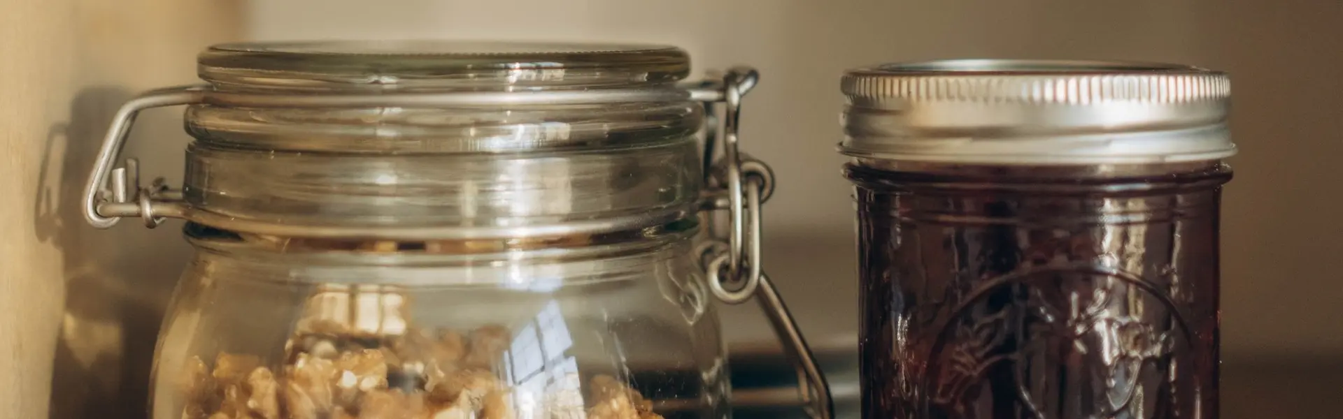 Tarros de cristal con nueces y mermelada en una alacena de madera clara