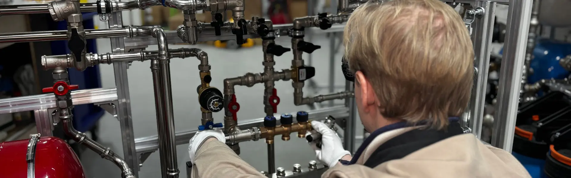 Técnico de guantes blancos ajustando la valvulería de latón de un equipo de calefacción en el taller